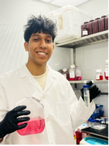 Aditya Shah in lab smiling, holding red liquid